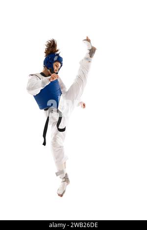 Atletica giovane ragazza con dobok e casco blu che pratica, allenamento taekwondo isolato su sfondo bianco Foto Stock