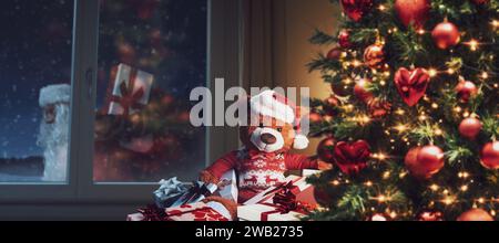Grazioso orsacchiotto a casa che aspetta Babbo Natale la vigilia di Natale, le feste e le celebrazioni Foto Stock
