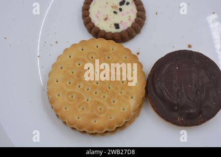 Biscotti di marca di vari tipi sono disposti in un piatto di vetro bianco. Foto Stock