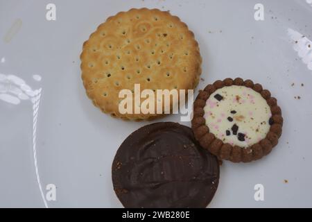 Biscotti di marca di vari tipi sono disposti in un piatto di vetro bianco. Foto Stock