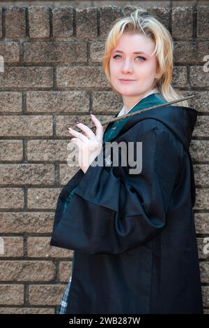 Una donna bionda caucasica vestita da mago con una bacchetta magica Foto Stock