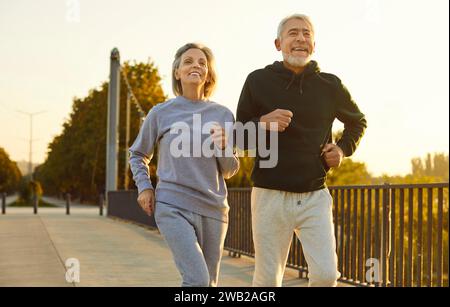 Persone anziane felici e sorridenti che indossano abbigliamento sportivo, fanno jogging all'aperto e fanno esercizio sportivo. Foto Stock