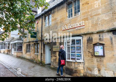 Caccia alle case nei cotswolds, modella rilasciata donna che guarda case in vendita nella finestra degli agenti immobiliari, Inghilterra, Regno Unito, 2023 Foto Stock