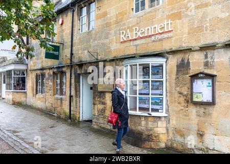 Caccia alle case nei cotswolds, modella rilasciata donna che guarda case in vendita nella finestra degli agenti immobiliari, Inghilterra, Regno Unito, 2023 Foto Stock