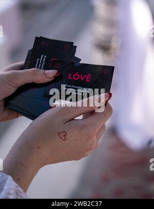 Una donna con le mani alzate davanti a lei, che tiene in mano carte nere con la parola "amore" Foto Stock