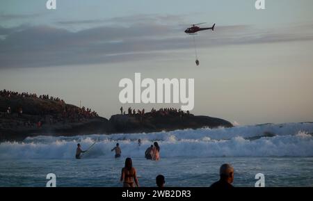 Rio de Janeiro, Rio de Janeiro, Brasile. 7 gennaio 2024. Il Rio de Janeiro Air Sea Rescue ha eseguito con successo un'operazione di salvataggio al tramonto sulla spiaggia di Ipanema, salvando un nuotatore in difficoltà. Sullo sfondo delle pietre di Arpoador, un elicottero ha portato l'individuo salvato davanti a centinaia di persone che si riuniscono ogni giorno per assistere agli splendidi tramonti. Questo incidente ha sottolineato l'intensa attività nelle acque di Rio dall'inizio del nuovo anno, con un notevole aumento delle operazioni di salvataggio che rispondono alle condizioni di surf. (Immagine di credito: © Bob Karp/ZUMA Press Wire) SOLO USO EDITORIALE! Foto Stock