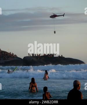 Rio de Janeiro, Rio de Janeiro, Brasile. 7 gennaio 2024. Il Rio de Janeiro Air Sea Rescue ha eseguito con successo un'operazione di salvataggio al tramonto sulla spiaggia di Ipanema, salvando un nuotatore in difficoltà. Sullo sfondo delle pietre di Arpoador, un elicottero ha portato l'individuo salvato davanti a centinaia di persone che si riuniscono ogni giorno per assistere agli splendidi tramonti. Questo incidente ha sottolineato l'intensa attività nelle acque di Rio dall'inizio del nuovo anno, con un notevole aumento delle operazioni di salvataggio che rispondono alle condizioni di surf. (Immagine di credito: © Bob Karp/ZUMA Press Wire) SOLO USO EDITORIALE! Foto Stock