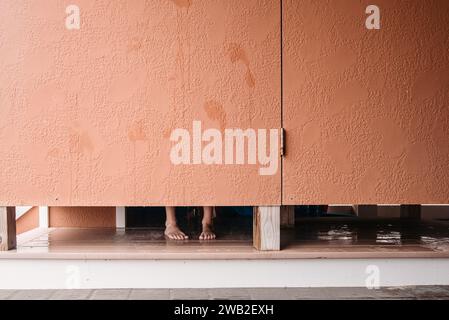 Piedi visibili sotto la porta della doccia esterna Foto Stock