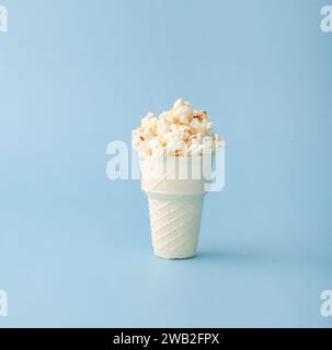 Cono waffle riempito con popcorn su sfondo blu Foto Stock