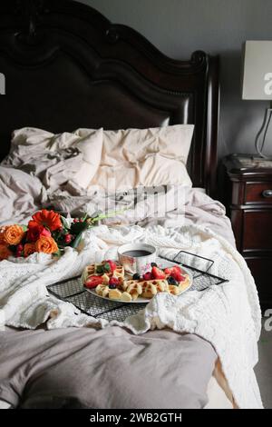 Waffle e caffè su un piatto e fiori per colazione a letto Foto Stock