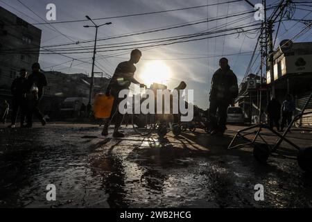 Rafah, territori palestinesi. 8 gennaio 2024. I palestinesi sfollati tengono bottiglie e taniche per riempirli di acqua. Le organizzazioni caritative distribuiscono acqua alle persone colpite dalla guerra a Gaza. Crediti: Abed Rahim Khatib/dpa/Alamy Live News Foto Stock