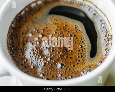 Vista dall'alto dall'alto, tazza bianca di caffè appena fatto con appetitosa schiuma di caffè marrone Foto Stock