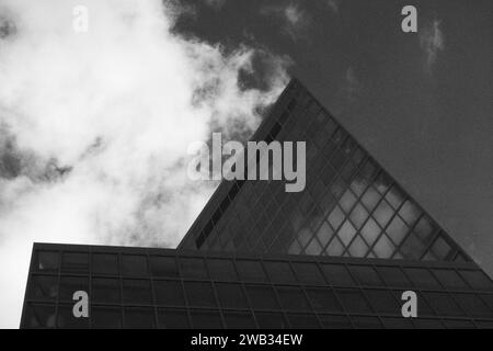 Splendida fotografia in bianco e nero che cattura il bordo nitido di un grattacielo contemporaneo contro un cielo dinamico, enfatizzando il contrasto tra ingegneria umana e bellezza naturale Foto Stock