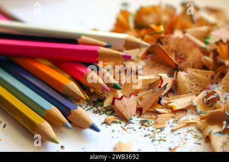 Matite colorate e trucioli di matite affilanti. Sfondo colorato per trucioli. Sfondo del disegno e della tavola scolastica. Concetto di creatività. Foto Stock
