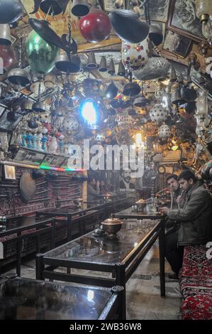 Azadegan Teahouse a Isfahan, Iran. I clienti che fumano narghilè. Soffitto e pareti decorate con una buona collezione di antiquariato, dipinti e foto. Foto Stock