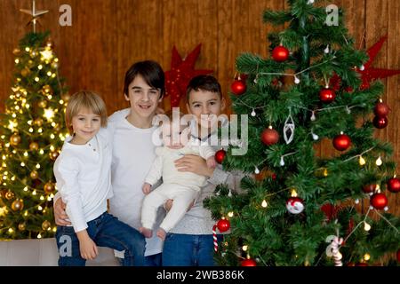 Famiglia felice, neonato e fratelli maggiori, mamma a casa a Natale Foto Stock