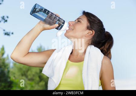 donna che si forma in forma beve acqua dopo aver fatto jogging la mattina Foto Stock