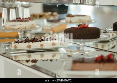 Un classico tavolo in legno con quattro piatti rotondi in vetro trasparente adornati con una varietà di deliziosi dessert Foto Stock