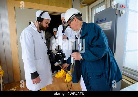 Tecnico addetto alla misurazione dei livelli di radiazioni sulle apparecchiature del giornalista dopo aver visitato l'edificio della centrale nucleare di Chornobyl (ChNPP). 20 aprile 2018. Foto Stock