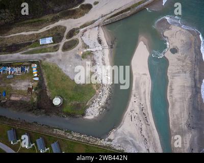 Sbocco fluviale verso il mare a Pentewan Cornovaglia con sponde di sabbia che proteggono la riva Foto Stock