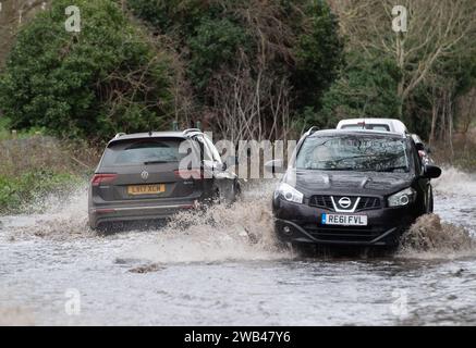 Horton, Wraysbury, Berkshire, Regno Unito. 8 gennaio 2024. Gli automobilisti guidano attraverso le acque alluvionali su una strada di campagna a Horton, Wraysbury, Berkshire. Il Tamigi ha fatto irruzione sulle sue sponde e vi sono una serie di chiusure stradali nell'area locale. Credito: Maureen McLean/Alamy Live News Foto Stock