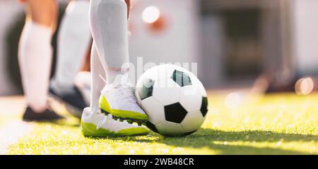 Pallone da calcio in movimento calciato da un giocatore di calcio. Sfondo orizzontale calcio europeo. Giocatore con scarpe da calcio e calze da calcio bianche. Momento di fo Foto Stock