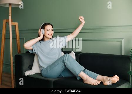 Giovane donna felice con le cuffie wireless che ascolta musica mentre balla. Euphoria ritmica. Joyful Woman che ama la musica con le cuffie wireless Foto Stock