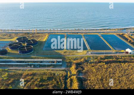 Vista aerea del moderno impianto di depurazione in riva al mare. Trattamento delle acque industriali con serbatoi d'acqua rotondi per il riciclaggio delle acque reflue dalla vista dei droni Foto Stock