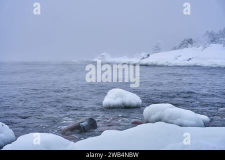 Uno splendido paesaggio invernale caratterizzato da un tranquillo specchio d'acqua circondato da neve e ghiaccio Foto Stock