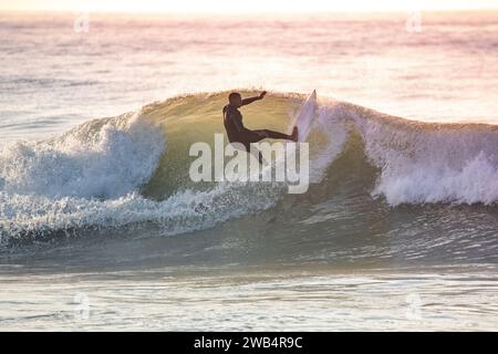 Giovane surfista con muta che si gode grandi onde. Foto Stock