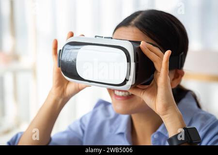Giovane coreana con occhiali VR che gioca a videogame interattivi per computer Foto Stock