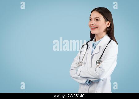 Felice giovane medico con stetoscopio su sfondo blu, spazio copia Foto Stock
