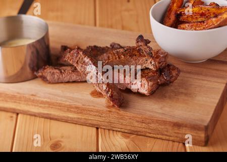 Fette di succosa bistecca di manzo con spicchi di patate e salsa di bistecche di funghi. Foto Stock