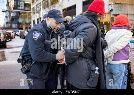 NEW YORK, NEW YORK - 8 GENNAIO: un ufficiale di polizia mette le manette sui polsi di un manifestante pro-Palestina dove i manifestanti chiudono l'ingresso del tunnel Holland diretto nel New Jersey a Lower Manhattan durante un sit-in che chiede la liberazione palestinese e un cessate il fuoco permanente l'8 gennaio 2024 a New York City. La protesta è stata una di una serie di azioni coordinate che hanno avuto luogo simultaneamente in altri tre principali attraversamenti di New York, tra cui il ponte di Brooklyn, il ponte di Manhattan e il ponte di Williamsburg, dove oltre 300 persone sono state arrestate e il traffico è stato bloccato Foto Stock