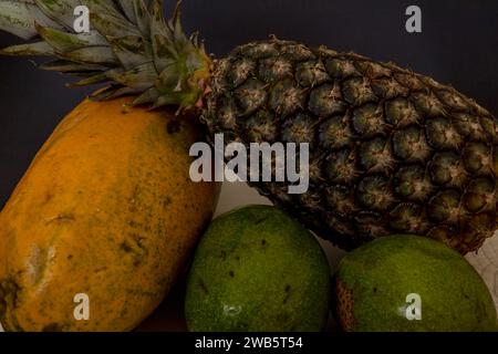 Ananas verde con papaia e avocado su sfondo scuro Foto Stock