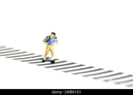 Fotografia in miniatura di giocattoli per persone piccole. Un ragazzo studente dell'asilo che corre su una zebra. Isolato su sfondo bianco. Foto immagine Foto Stock