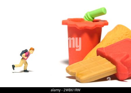 Fotografia di figure giocattolo per persone in miniatura. Concetto di cibo sano mangiare e pausa pranzo. Un ragazzo che corre verso uno spuntino al cioccolato e una bevanda analcolica. Isolato su wh Foto Stock