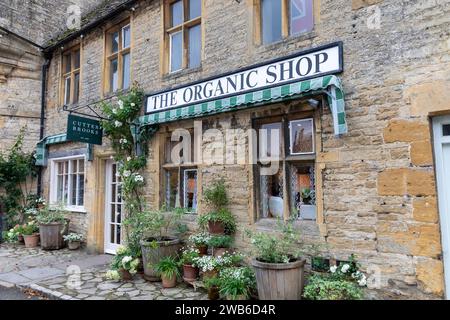 Riponi il mercato della città di Wold cotswolds con il negozio di alimentari Organic Shop nella piazza del mercato, Gloucestershire, Inghilterra, Regno Unito, 2023 Foto Stock