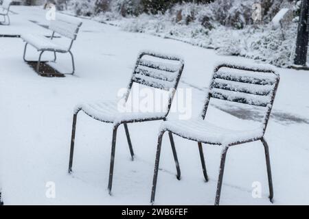 San Gallo, Svizzera, 28 novembre 2023 neve fresca sta cadendo sulle sedie nell'orto botanico Foto Stock