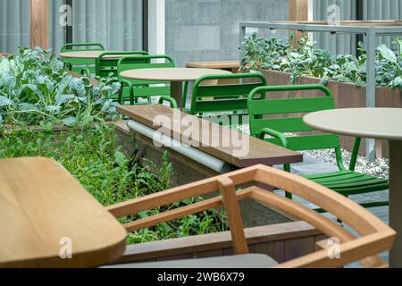 Caffè all'aperto, tavoli vuoti e sedie con piante verdi. Foto Stock
