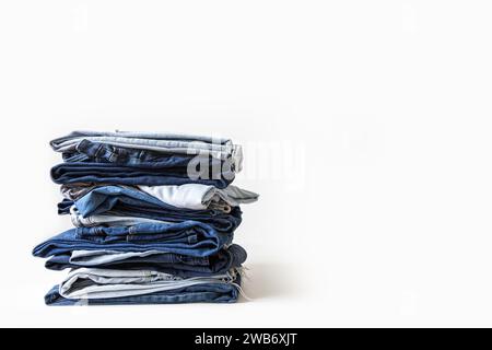 Pila di varie tonalità di jeans blu su sfondo bianco Foto Stock