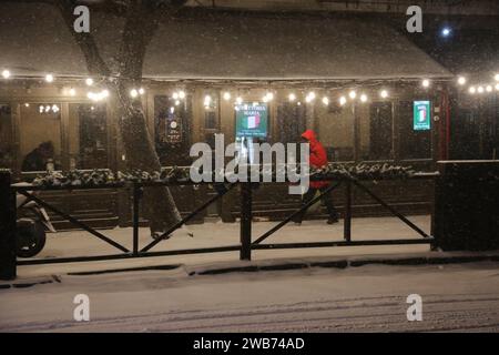 Odessa, Ucraina. 8 gennaio 2024. Un uomo cammina davanti a un caffè di strada su Sadovaya Street in una tempesta di neve. A Odessa, dall'ora di pranzo dell'8 gennaio 2024, il tempo peggiorò bruscamente, la pioggia si trasformò in neve e la temperatura calò. A questo proposito, le autorità cittadine si appellarono ai residenti della città con una richiesta, se possibile, di limitare il movimento intorno alla città a piedi e in auto e di trasferire i lavoratori al lavoro a distanza. Credito: SOPA Images Limited/Alamy Live News Foto Stock