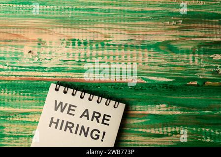 Notebook con We Are Hiring testo su un tavolo di legno. Concetto di gestione delle risorse umane Foto Stock