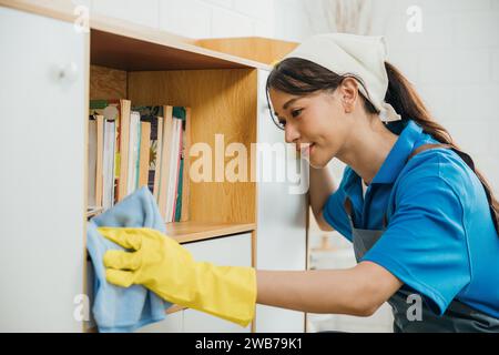 Con un sorriso donna diligente in panni gialli per guanti e mantiene il tavolo nel suo spazio abitativo. Lei Foto Stock