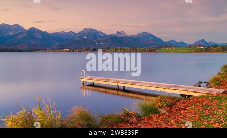 Alba autunnale con un molo sul lago Hopfen con le Alpi Allgauer sullo sfondo. Il lago Hopfen si trova vicino alla città di Füssen in Baviera, a sud Foto Stock