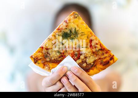 Una giovane ragazza con trecce è mangiare un pezzo di pizza Foto Stock