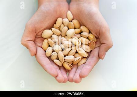 ragazza con gustosi pistacchio arrosto su sfondo bianco, vista dall'alto Foto Stock
