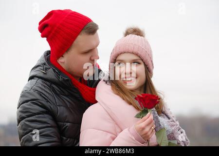 Un uomo dà una rosa rossa a una giovane donna. Il concetto di San Valentino Foto Stock