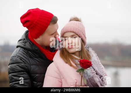 Un uomo dà una rosa rossa a una giovane donna. Il concetto di San Valentino Foto Stock