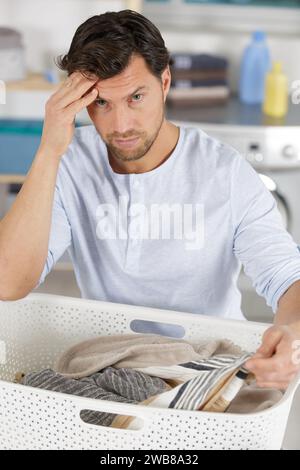 un uomo frustrato che tiene il cesto pieno di vestiti Foto Stock